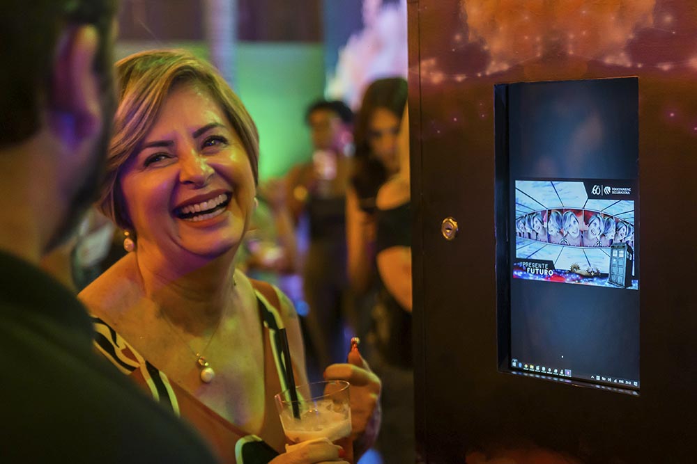 participante de evento da Tokio Marine sorri ao ver o resultado de seu vídeo feito na tela do equipamento